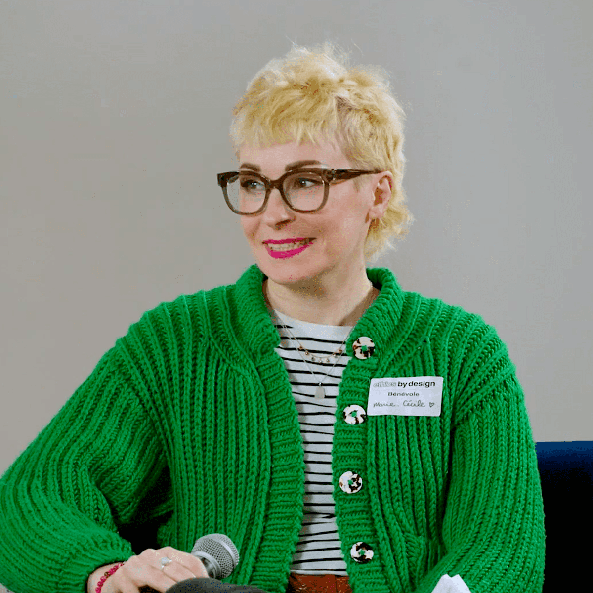 Portrait of Marie-Cécile taken during Ethics By Design 2022. She is smiling, wearing a green cardigan, platinum blonde hair and glasses.